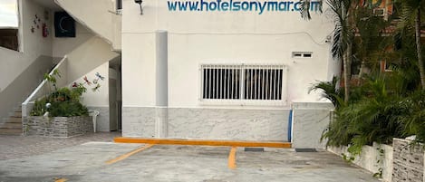 A hotel entrance with a sign, a staircase, and a parking area.