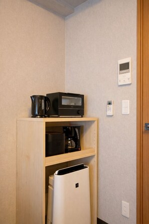 Eine Küchenzeile mit Mikrowelle, Kaffeemaschine und kleinem Kühlschrank.
