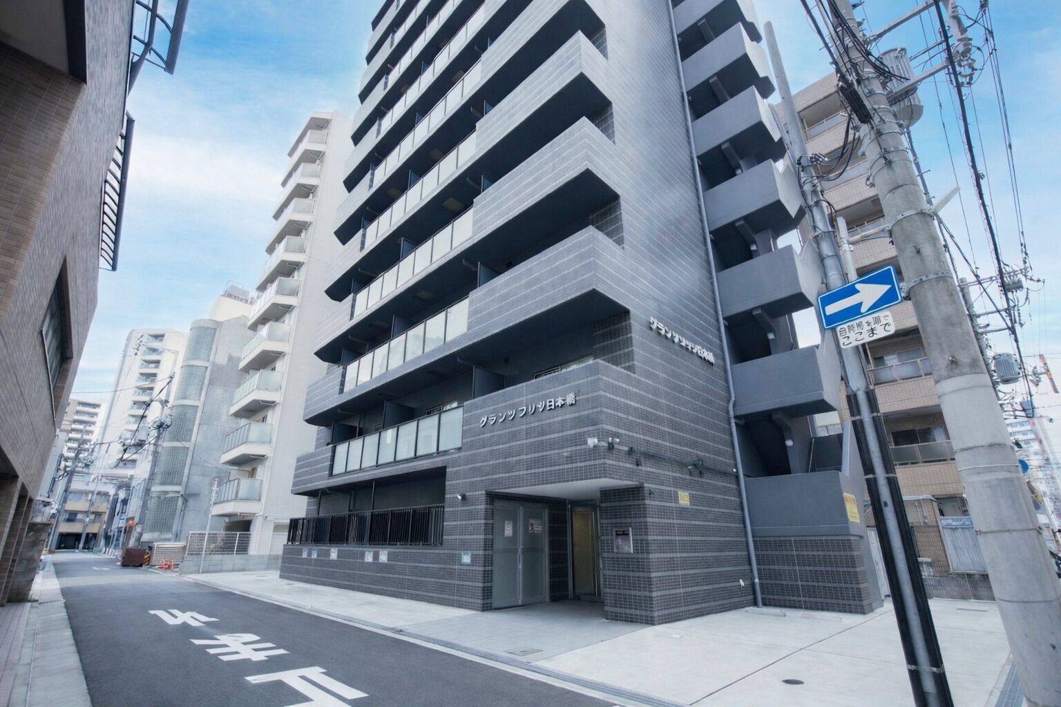 Un edificio moderno de varios pisos, con una entrada visible y un letrero que indica una dirección.