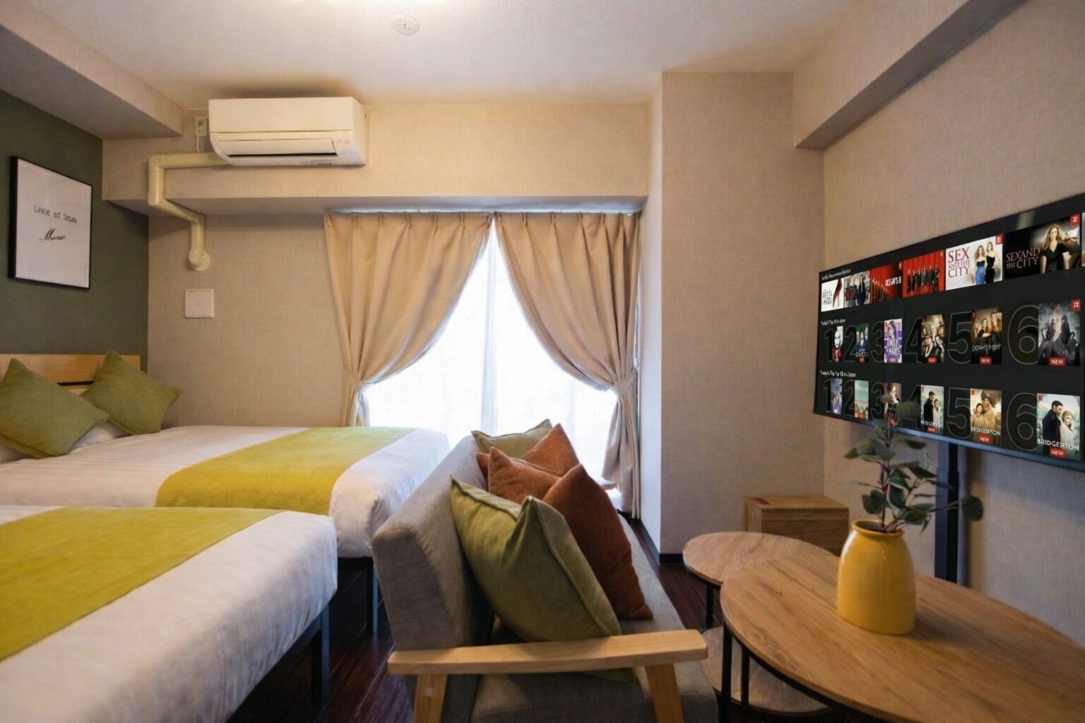 A hotel room with two beds, a small table, a plant, and a wall with movie posters.