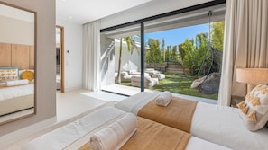 A modern bedroom with a large sliding glass door leading to a garden. - VILLA GLAMOUR BY VACATION MARBELLA (La Alquería, El Paraíso Benahavís,)