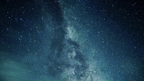 Un ciel nocturne étoilé où l’on peut distinguer une galaxie.