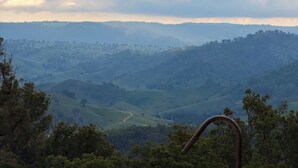 Une baignoire agrémentée d’un banc en bois rustique, d’un tronc d’arbre et offrant une vue panoramique sur des collines et des vallées verdoyantes.