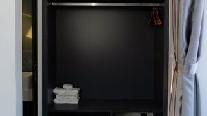 A walk-in closet with shelves, a hanging rod, and a trash bin. - Song Bien Beach Villa Homestay (Hoa Hiep)