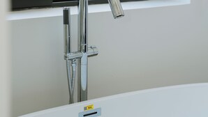 A modern bathroom with a chrome faucet, a visible water heater, and a window with a view of palm trees. - Song Bien Beach Villa Homestay (Hoa Hiep)