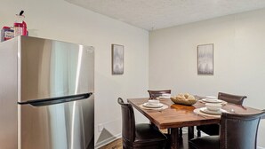A dining area with a wooden table, chairs, and a stainless steel refrigerator.