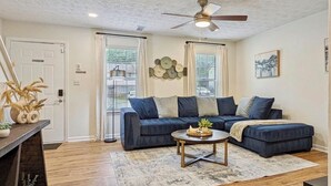 A living room with a dark blue sectional sofa, a round coffee table, and a ceiling fan.