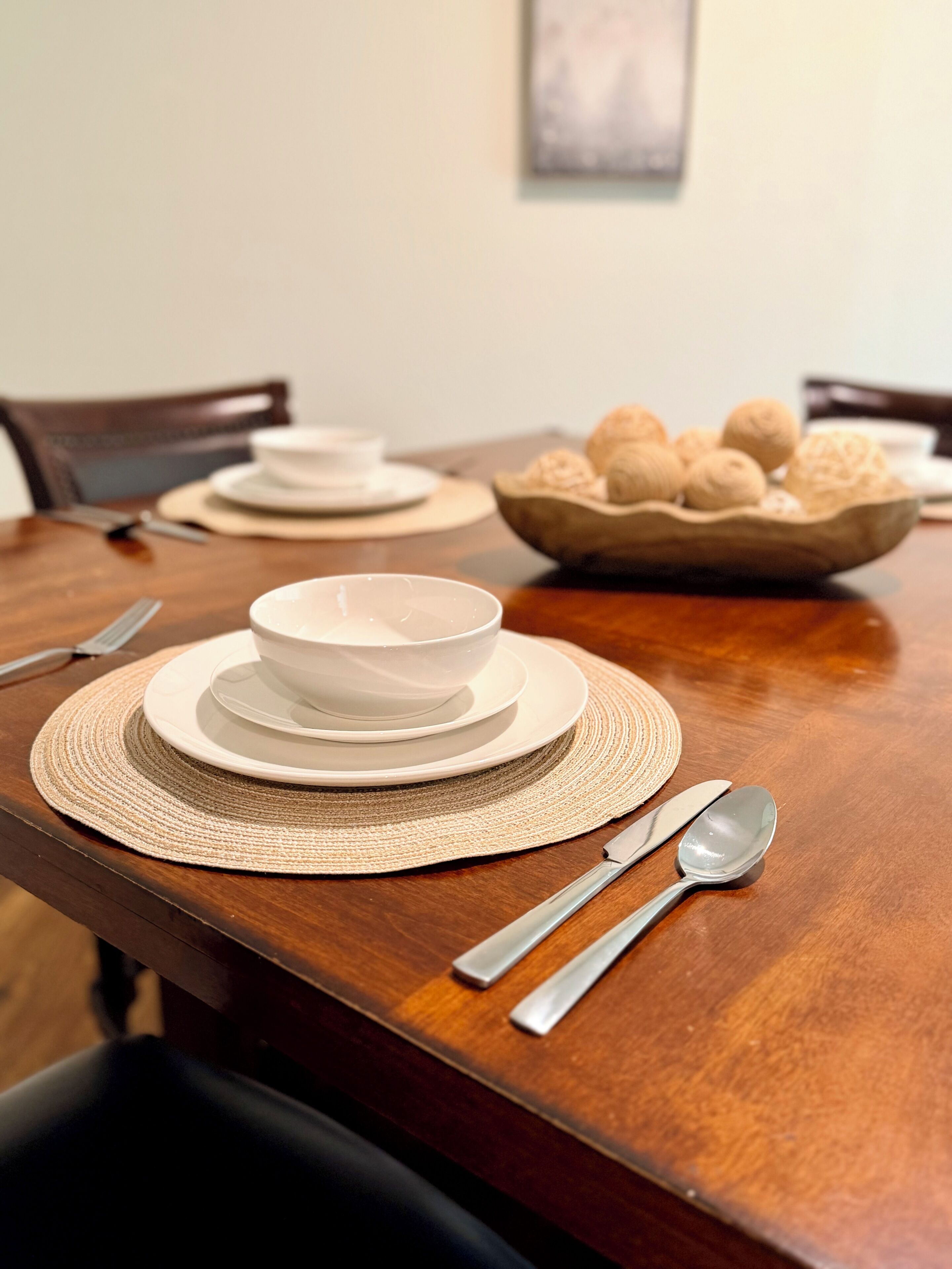 A dining table set with plates, bowls, and a bowl of cookies.