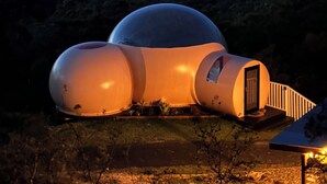 A spherical structure with a door, surrounded by a landscape with hills.
