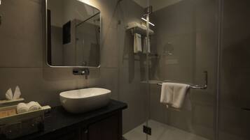 A modern bathroom with a large mirror, a sink, and a glass-enclosed shower area.