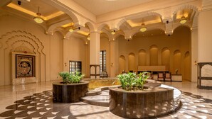Un hall espacioso con techos altos, arcos decorativos y un piso con diseño.