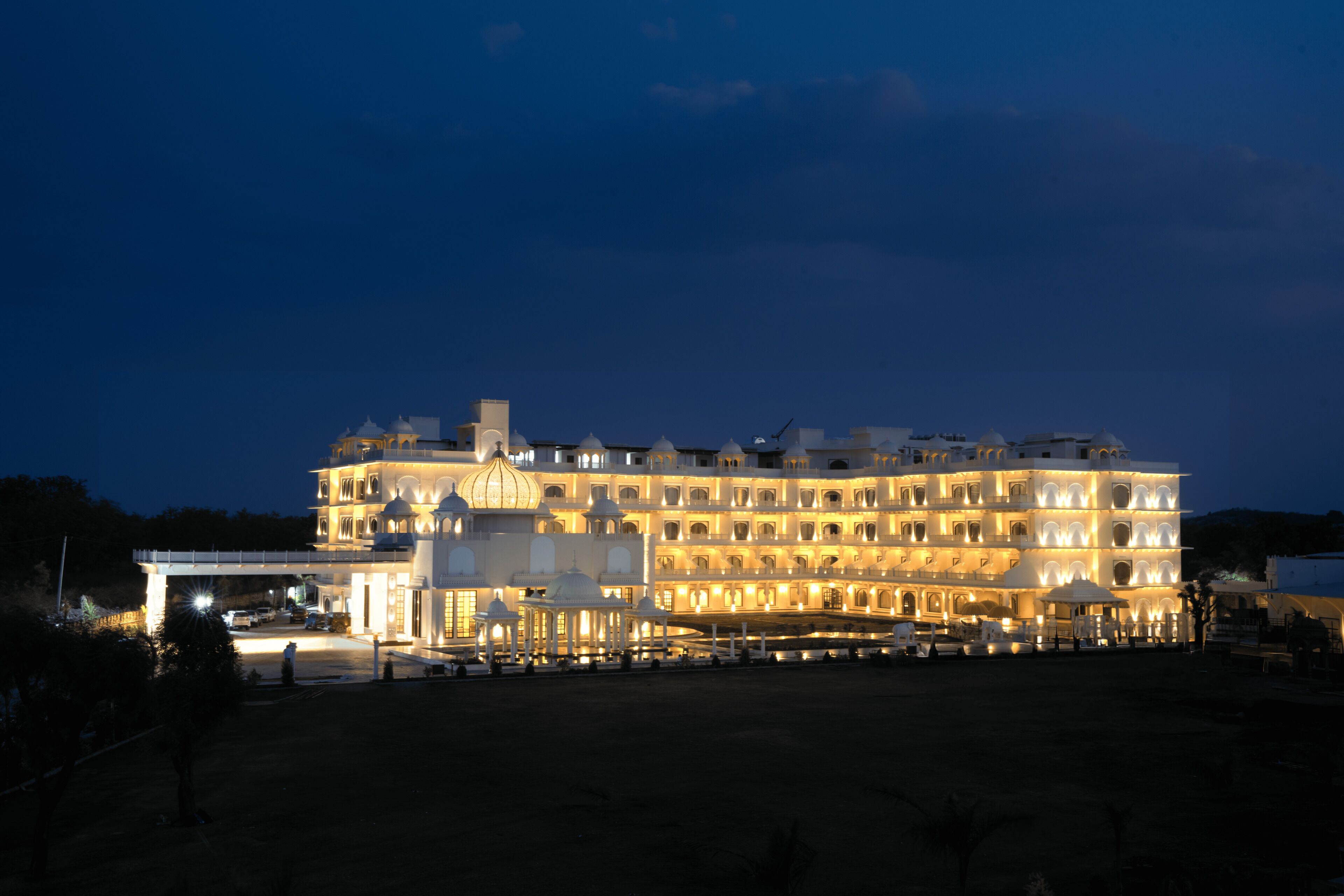 A large, multi-story hotel with a symmetrical facade, multiple balconies, and a well-lit entrance.