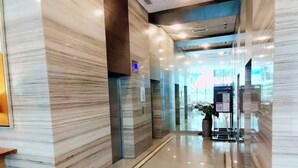 A modern hotel lobby with marble walls, a glass elevator, and a reception desk. - Luxury Studio 38 Park Ave (Cebu City)