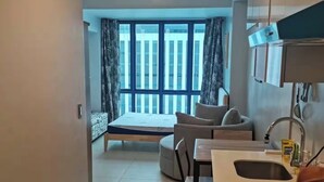 A modern apartment with a kitchen, a dining area, a sofa, and a large window with curtains. - Luxury Studio 38 Park Ave (Cebu City)