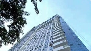A high-rise building with a modern design, featuring a prominent entrance with glass doors and a landscaped area with plants and spherical bollards. - Luxury Studio 38 Park Ave (Cebu City)