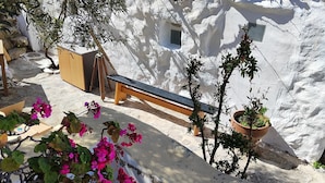 A stone wall with a wooden bench, a small window, and potted plants. - Artemis cottage Mykonos (Mikonos)