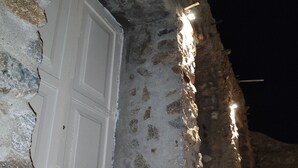 A stone building with a white door and a small bench. - Charming Holiday House in Mikonos with Garden View (Mikonos)