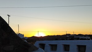 Een ondergaande zon boven een besneeuwd landschap, met gebouwen op de achtergrond.