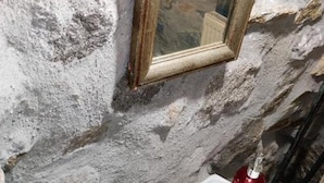 Kylpyhuoneessa on valkoinen pesuallas, peili ja punainen pullo.