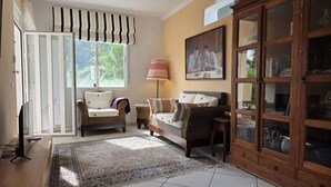 Ein Wohnzimmer mit einer Couch, einem Sessel und einem Schrank mit Glastüren.