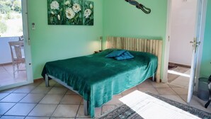 Ein Schlafzimmer mit Bett, einem Bild, einer Dekoration und Blick ins Freie.