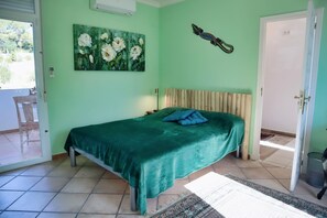 A bedroom with a bed, a painting, a decorative item, and a view of the outside. - Casita Palmera - Altea, Costa Blanca (Altea)