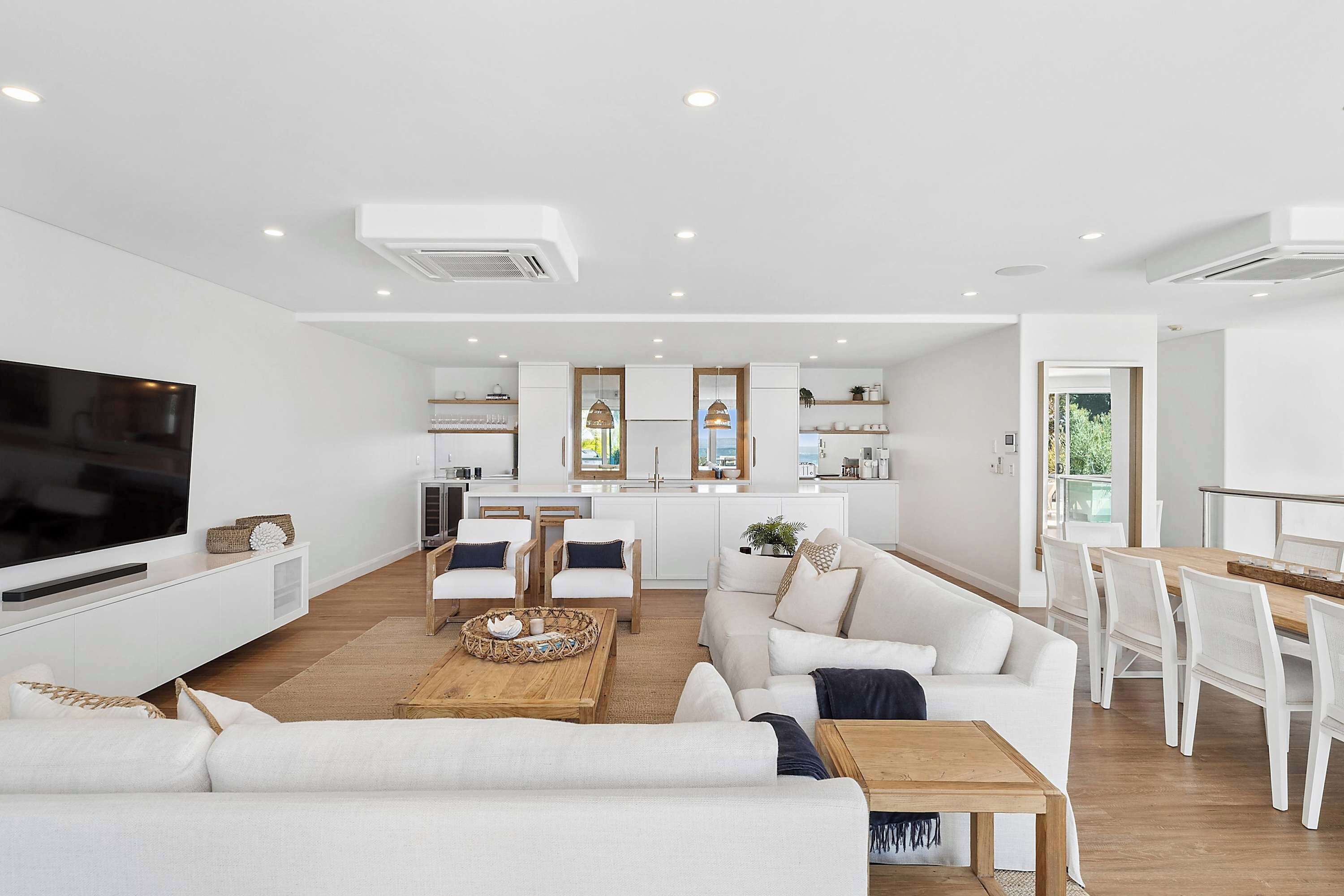 A modern living room with a TV, sofa, coffee table, and dining area.