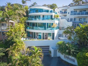 A multi-story building with balconies, a pool, and lush greenery. - Rhapsody by Coast Hosting (Terrigal)