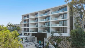 A multi-story hotel with balconies, a parking area, and a landscaped garden. - Avoca Lake View Luxury Apartment (Avoca Beach)