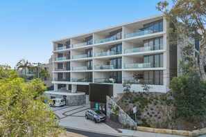 A multi-story hotel with balconies, a parking area, and a landscaped garden. - Avoca Lake View Luxury Apartment (Avoca Beach)