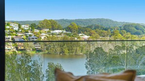 A view from a window overlooking a lake, with houses and trees in the background. - Avoca Lake View Luxury Apartment (Avoca Beach)