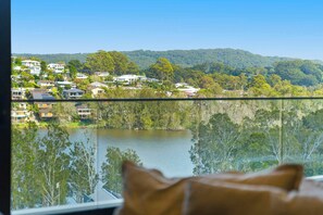 A view from a window overlooking a lake, with houses and trees in the background. - Avoca Lake View Luxury Apartment (Avoca Beach)
