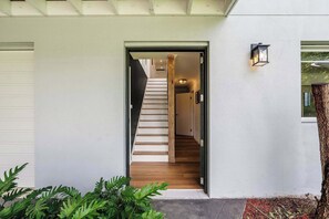 A modern house with a white exterior, a wooden staircase, and a small porch area. - Forresters Lodge by Coast Hosting (Forresters Beach)