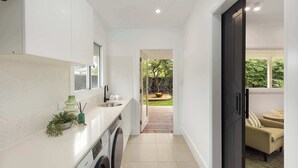Une petite cuisine étroite avec un lave-linge, un évier et une fenêtre.