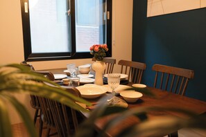 A dining table set with plates, glasses, and a vase of flowers.