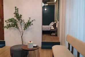 Ein modernes Zimmer mit Bett, Nachttisch, Lampe und einer kleinen Pflanze.