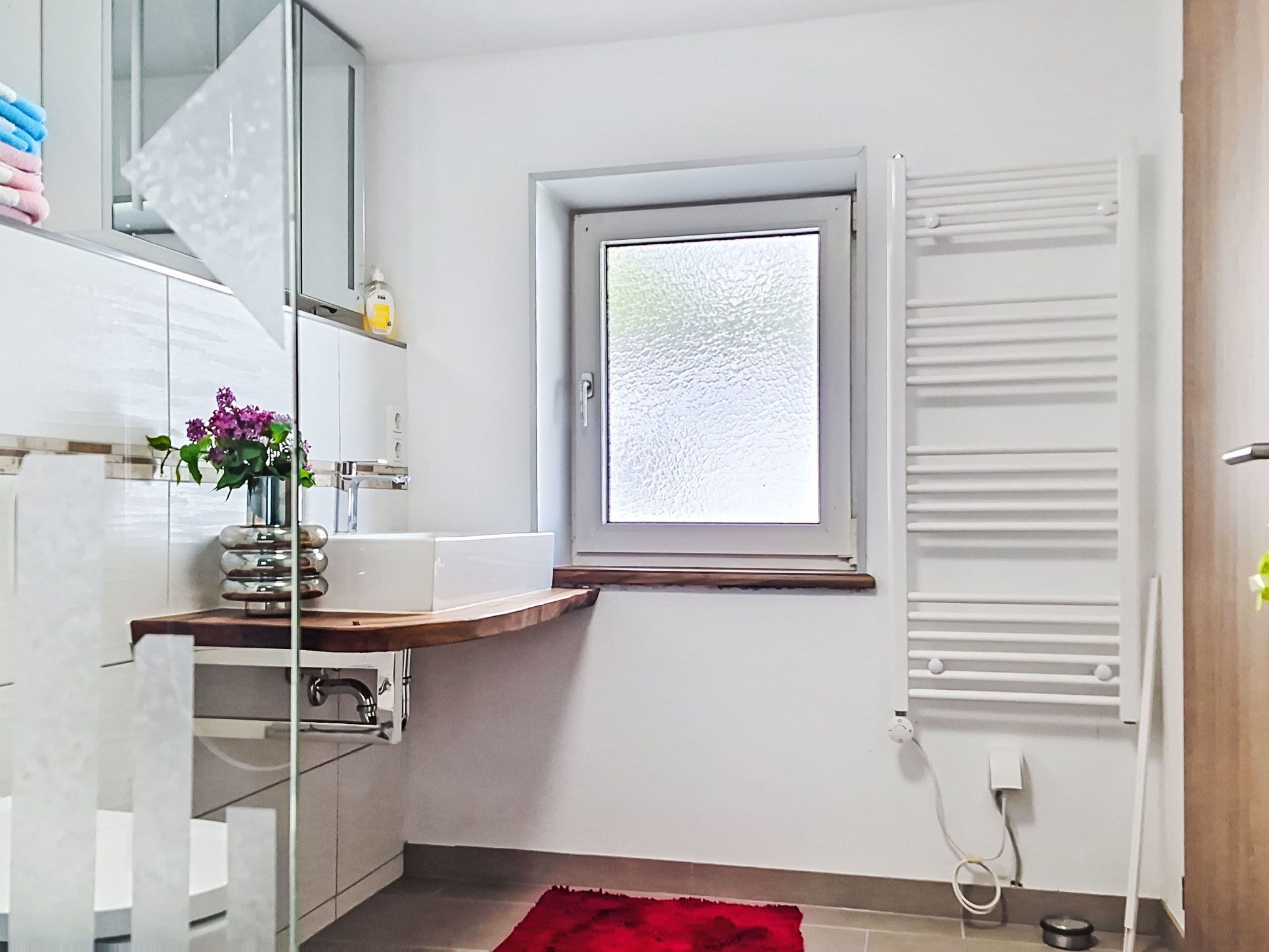Eine kleine Küche mit integriertem Spülbecken, einem Fenster und einem roten Teppich.