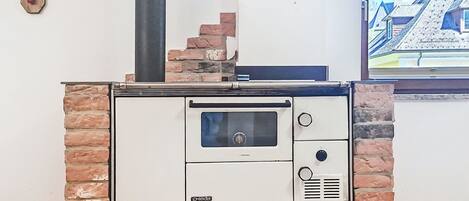 Une cuisine de style rétro, dotée d’un four encastré, d’un mur décoratif en briques et d’une fenêtre donnant sur les bâtiments environnants.