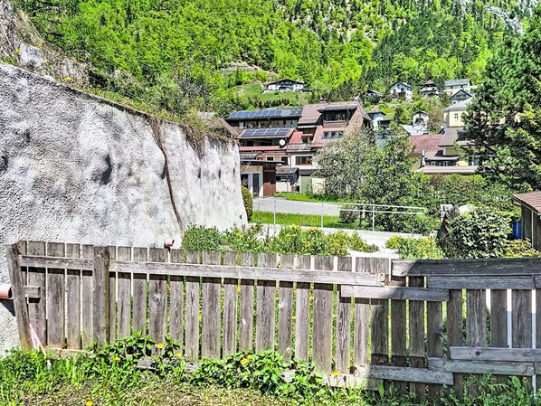 A residential area with houses, a wooden fence, and a large rock formation.