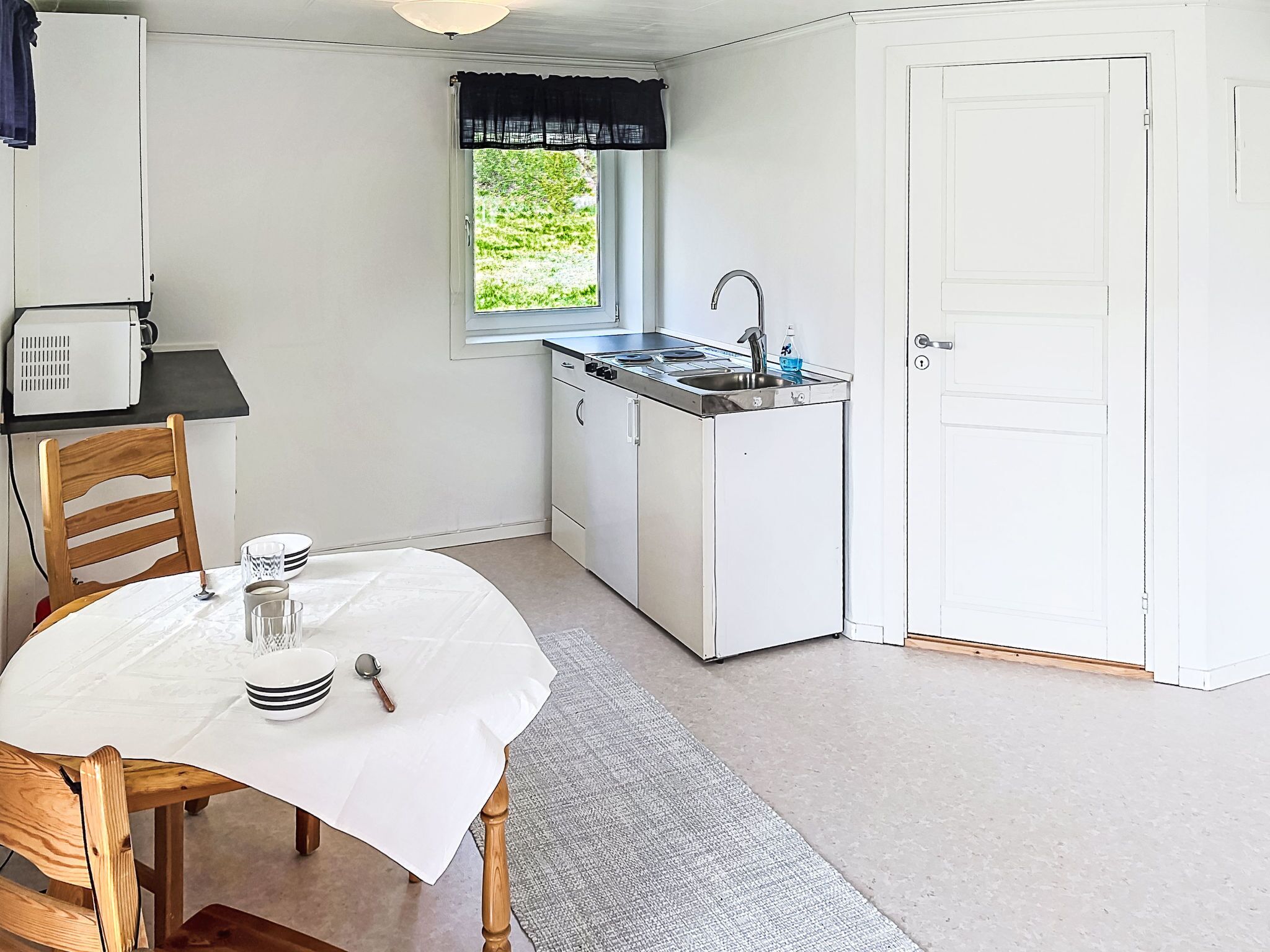 A compact kitchen with a window, a sink, and a dining table with chairs.