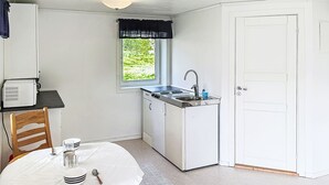 Eine kleine Küche mit Fenster, Spüle und einem Esstisch mit Stühlen.
