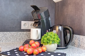 A kitchen counter with a coffee maker, a white mug, and a potted plant. - Depedance house Gisela with 3 bedrooms (Bann)