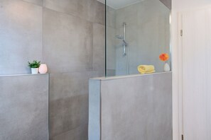 Ein modernes Badezimmer mit Duschkabine aus Glas, einer kleinen Pflanze und einer Vase mit einer Blume.