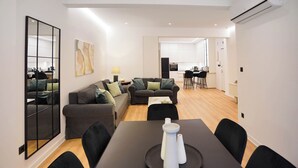 A modern living area with a dining table, sofas, and a kitchen in the background. - To Casa Krini είναιι ένα υπέροχο διαμέρισμα στο κέντρο του Ηρακλείου (Iraklio)
