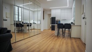 A modern kitchen with a refrigerator, a dining area with chairs, and a large mirror reflecting the space. - To Casa Krini είναιι ένα υπέροχο διαμέρισμα στο κέντρο του Ηρακλείου (Iraklio)