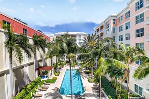 A pool surrounded by palm trees and buildings with balconies. - Moorings Pool Overview Resort (Lantana)