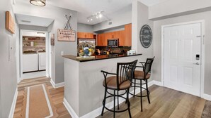 A modern kitchen with a central island, bar stools, and a hanging light fixture. - Moorings Pool Overview Resort (Lantana)