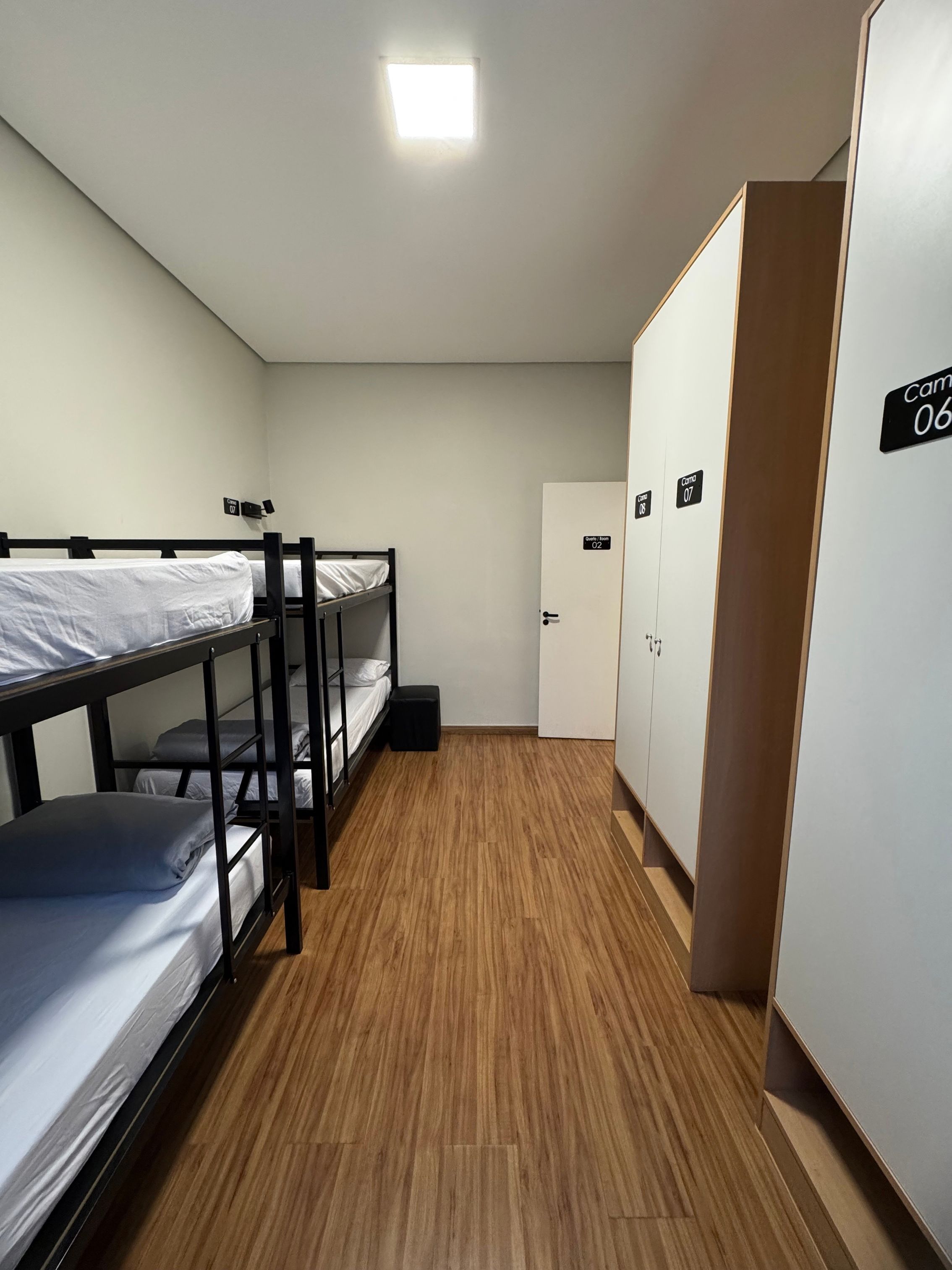 Un dormitorio con literas, un armario y una puerta con números de habitación.