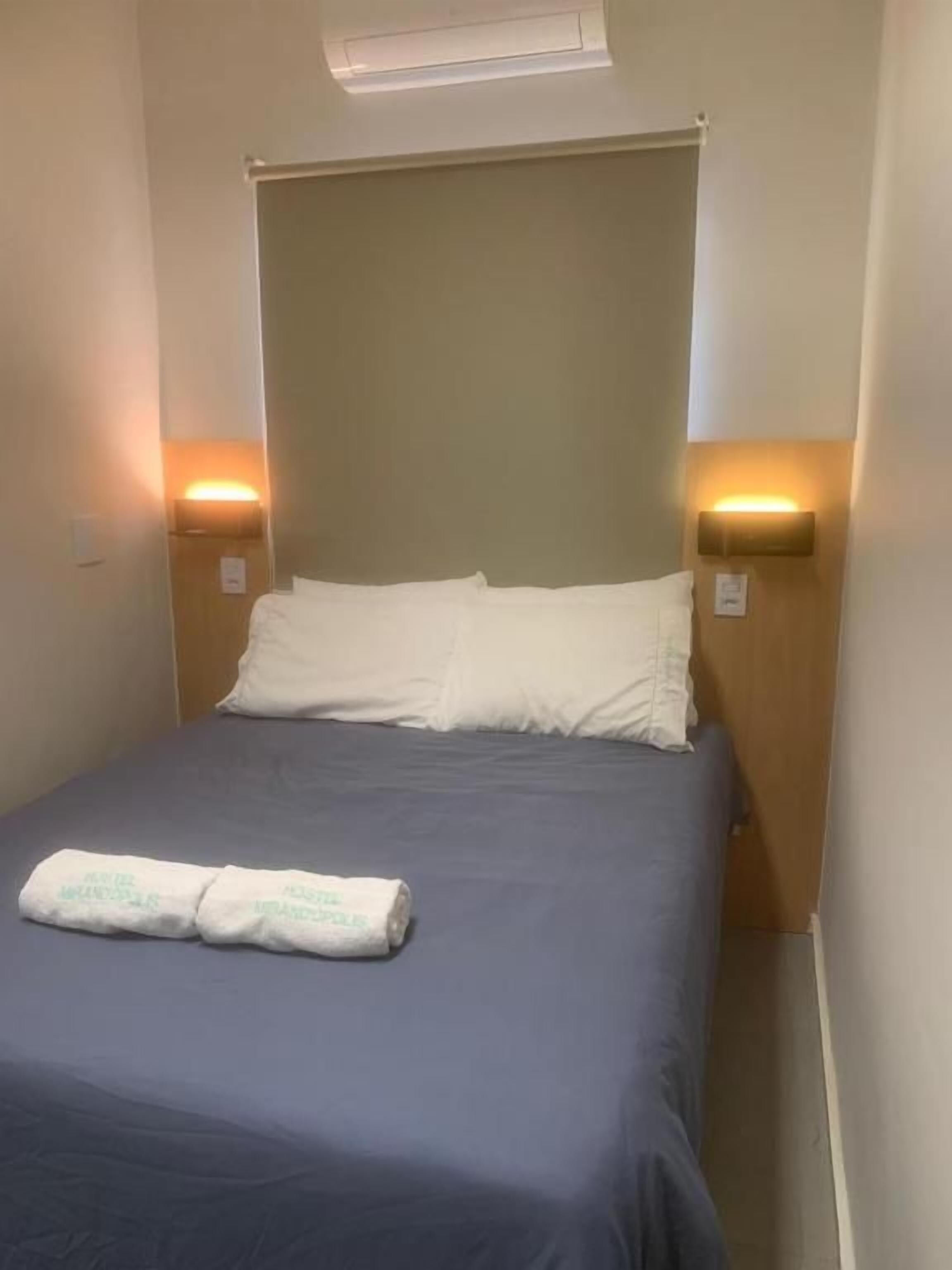 Een hotelkamer met een bed, twee bedlampen en een handdoek op het bed.