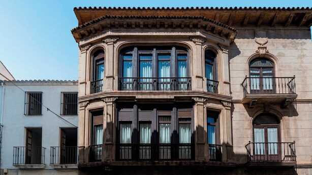 A corner building with a bay window, a balcony, and a door with a window.